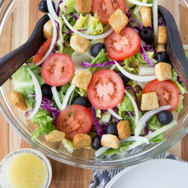 Olive Garden salad served in a white bowl with dressing on the side