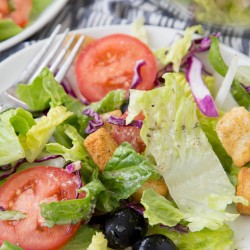 A close up of Olive Garden salad with tomatoes and croutons