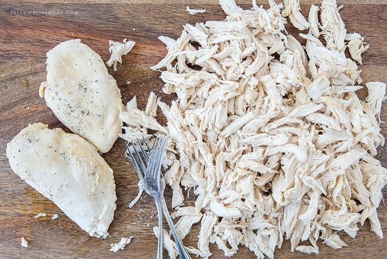 Chicken breasts cooked in a slow cooker then shredded on a cutting board