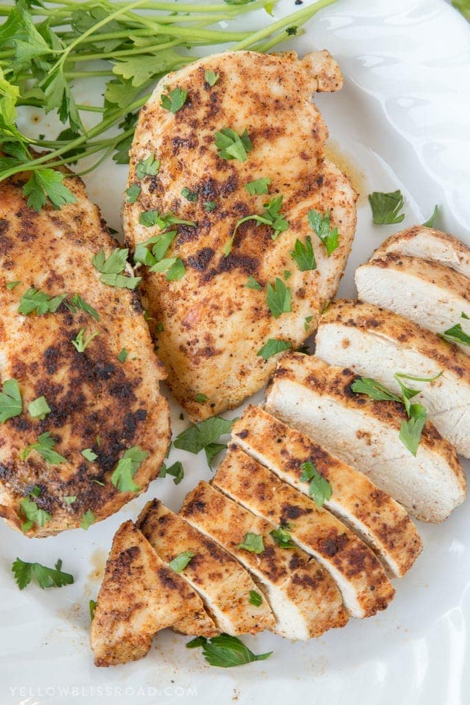 Juicy stovetop chicken breasts, slice on a plate with parsley