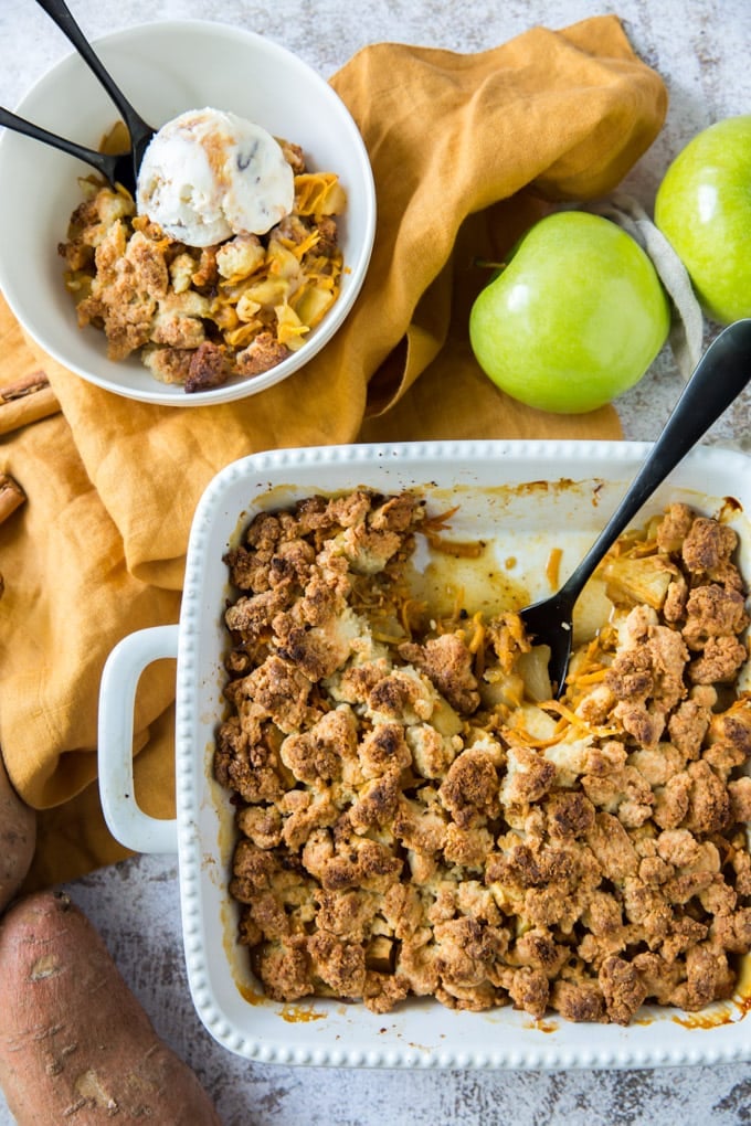 a dish of apple cobbler with a spoon in it next to a bowl of apple cobble with ice cream