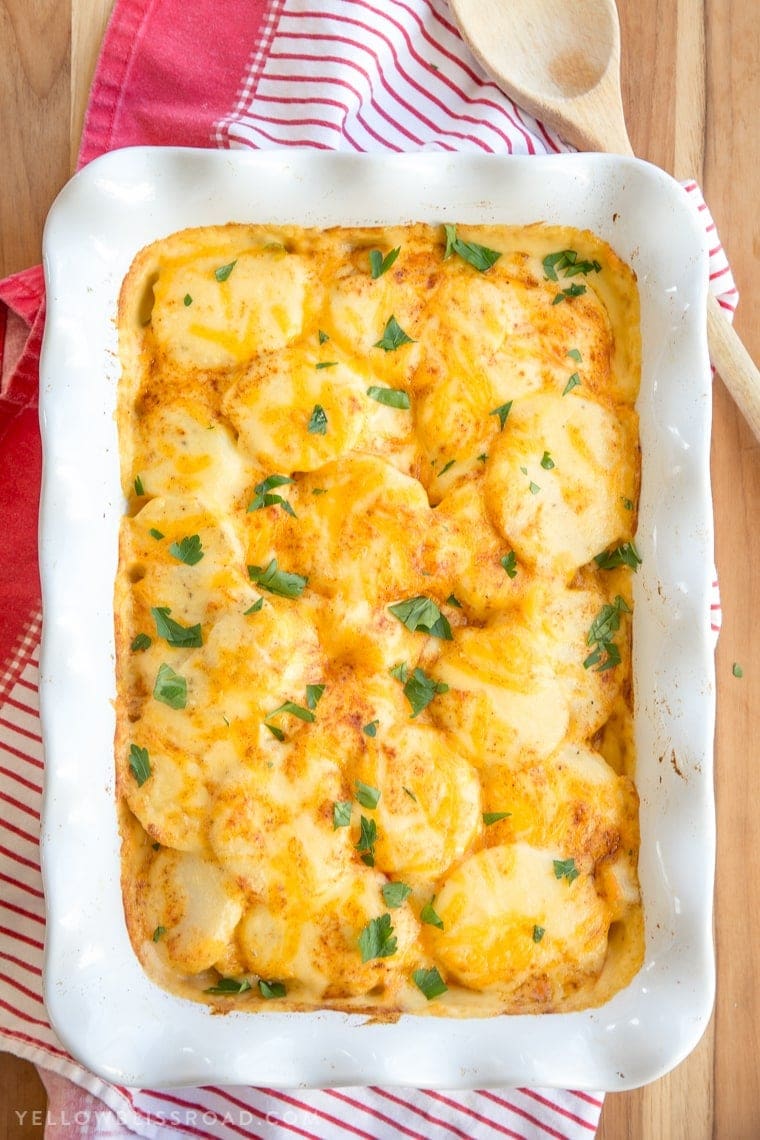 An overhead image of cheese covered sliced potatoes with paprika and parsley