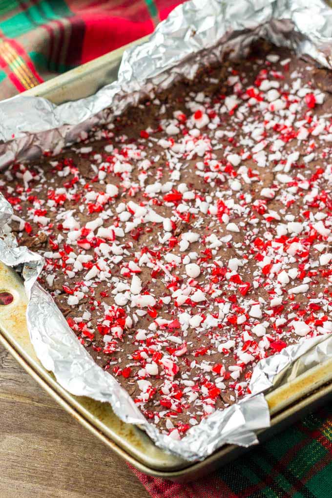 A square pan of peppermint fudge with crushed candy canes on top.