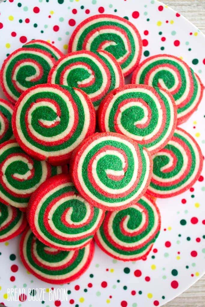 Rolled pinwheel christmas ookies in festive colors stacked on a plate.