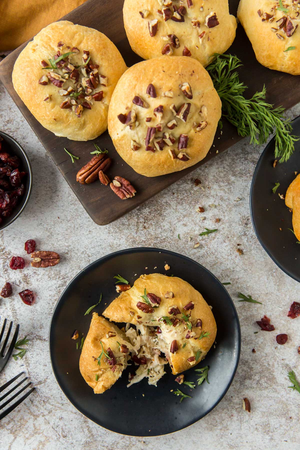 black plates, crescent dough with pecans, chicken, cranberries, cutting board