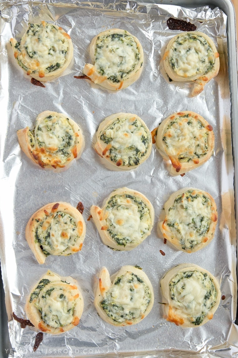 Creamy delicious Spinach Artichoke Dip Pinwheels on a baking sheet, just baked.