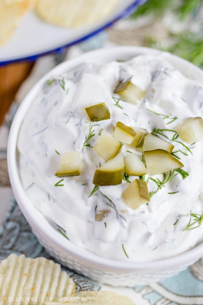 A close up image of dill pickle dip topped with chopped pickles.