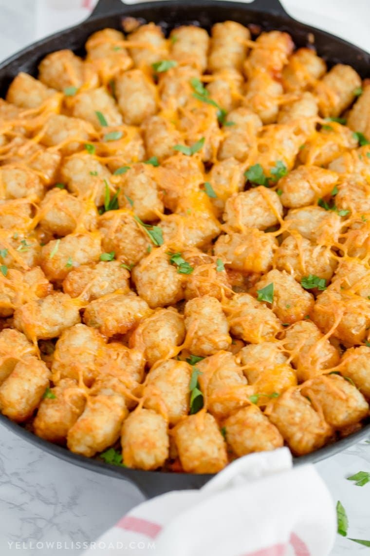 tater tots topped with cheese and arranged in a circle in a cast iron skillet