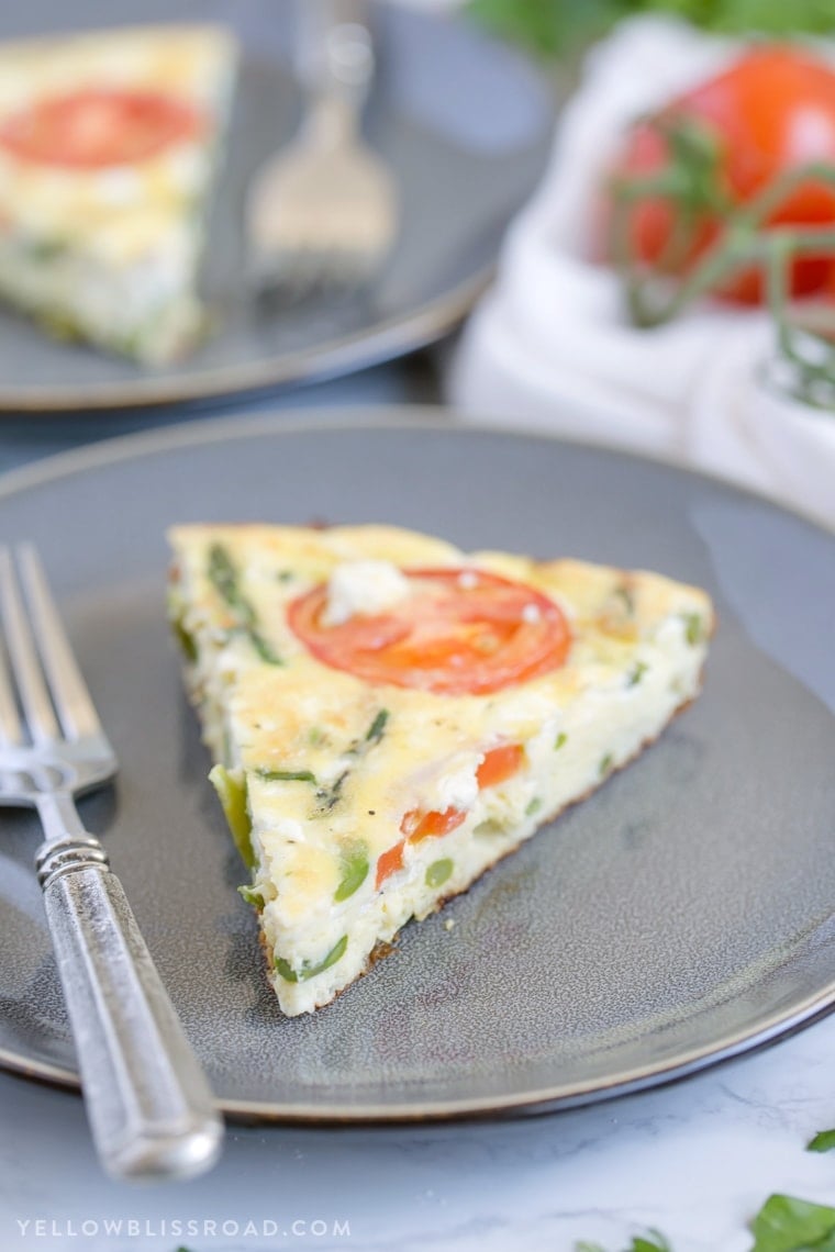 A slice of frittata on a gray plate with a fork