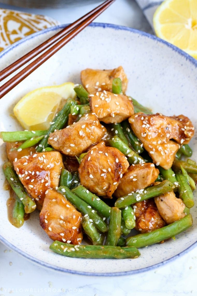 Honey Lemon Chicken and Green Beans in a bowl with chopsticks and lemons.