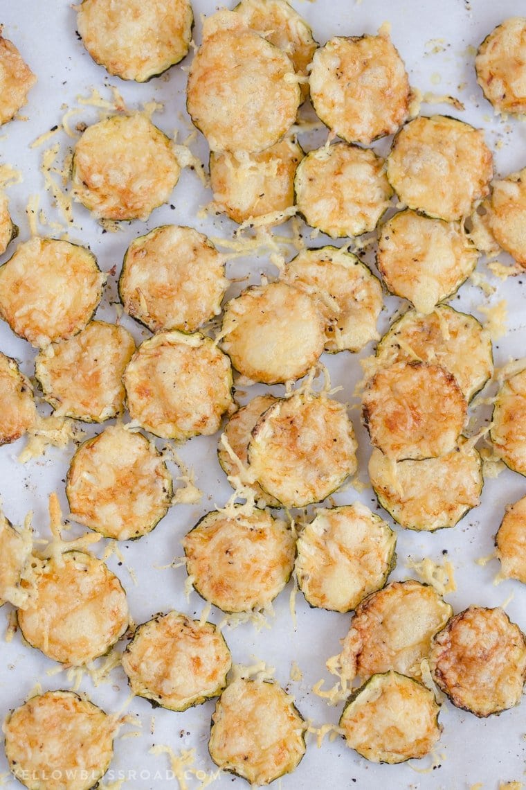 tons of zucchini chips on white parchment paper