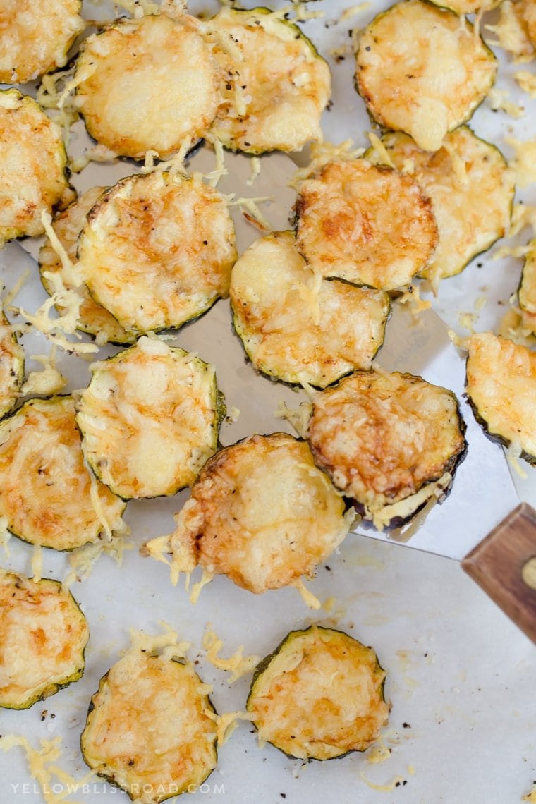 Baked Parmesan Zucchini Crisps are a highly addictive snack that is simple to make with just two ingredients! You'll love these healthy zucchini chips! a bunch of zucchini baked with parmesan cheese