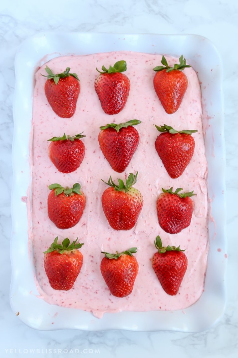 This Strawberries and Cream Poke Cake takes full advantage of Strawberry season with tons of fresh strawberries in the filling and the frosting. It's a strawberry lovers dream dessert!