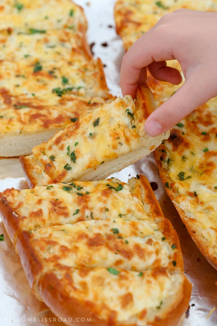 Cheesy Garlic Bread - Homemade garlic bread with a hand taking a slice.