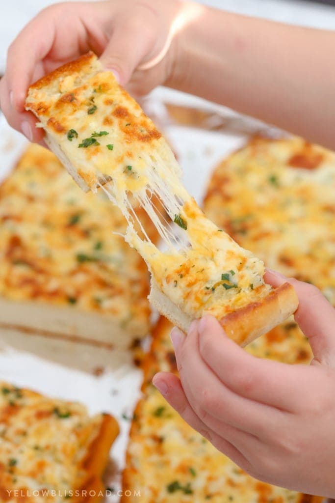 Turn plain french bread into cheesy, garlicky perfection with this epic Cheesy Garlic Bread with three kinds of cheese, herbs and tons of garlic.