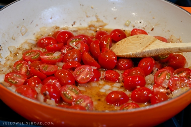tomatoes and onions cooking in a skillet