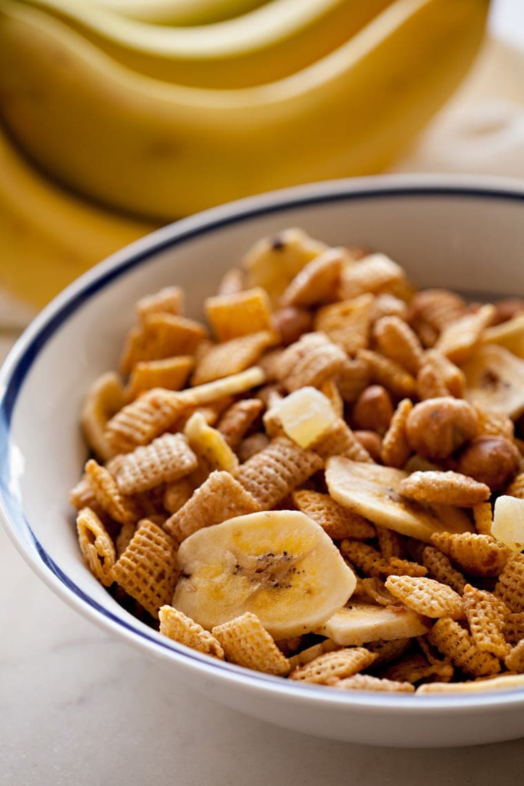 A bowl filled with banana chips, chex cereal and macadamia nits