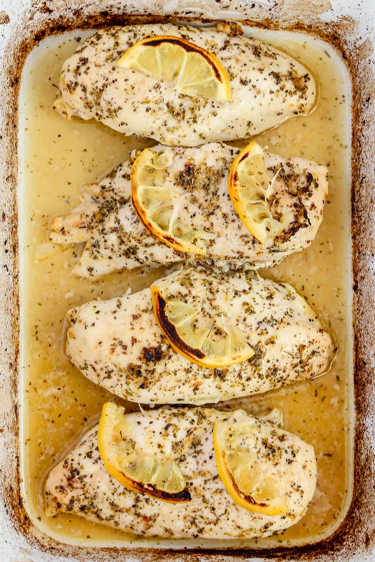 4 cooked chicken breasts with lemon slices.