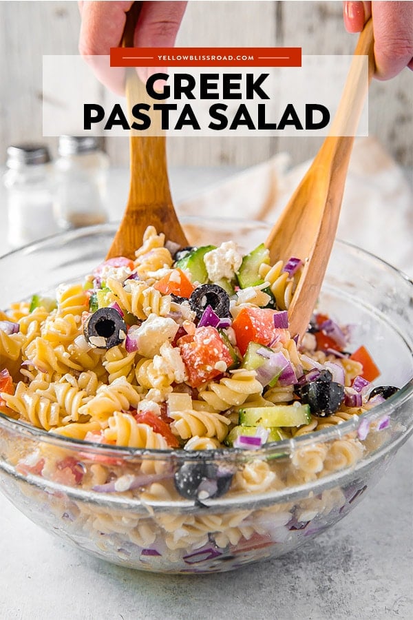 Greek pasta salad being tossed with salad tongs
