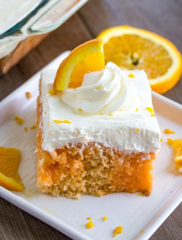 Slice of Orange Creamsicle Poke Cake with Whipped Cream Topping