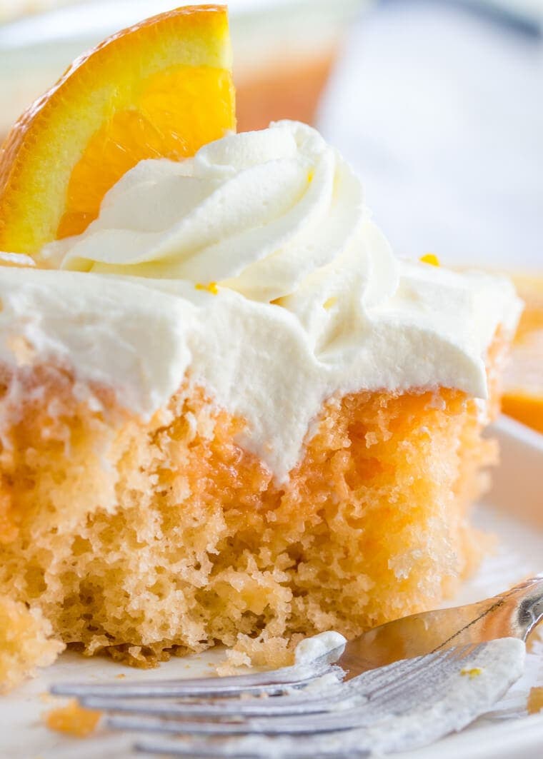 Close up slice of Orange Creamsicle Poke Cake with Whipped Cream Topping 