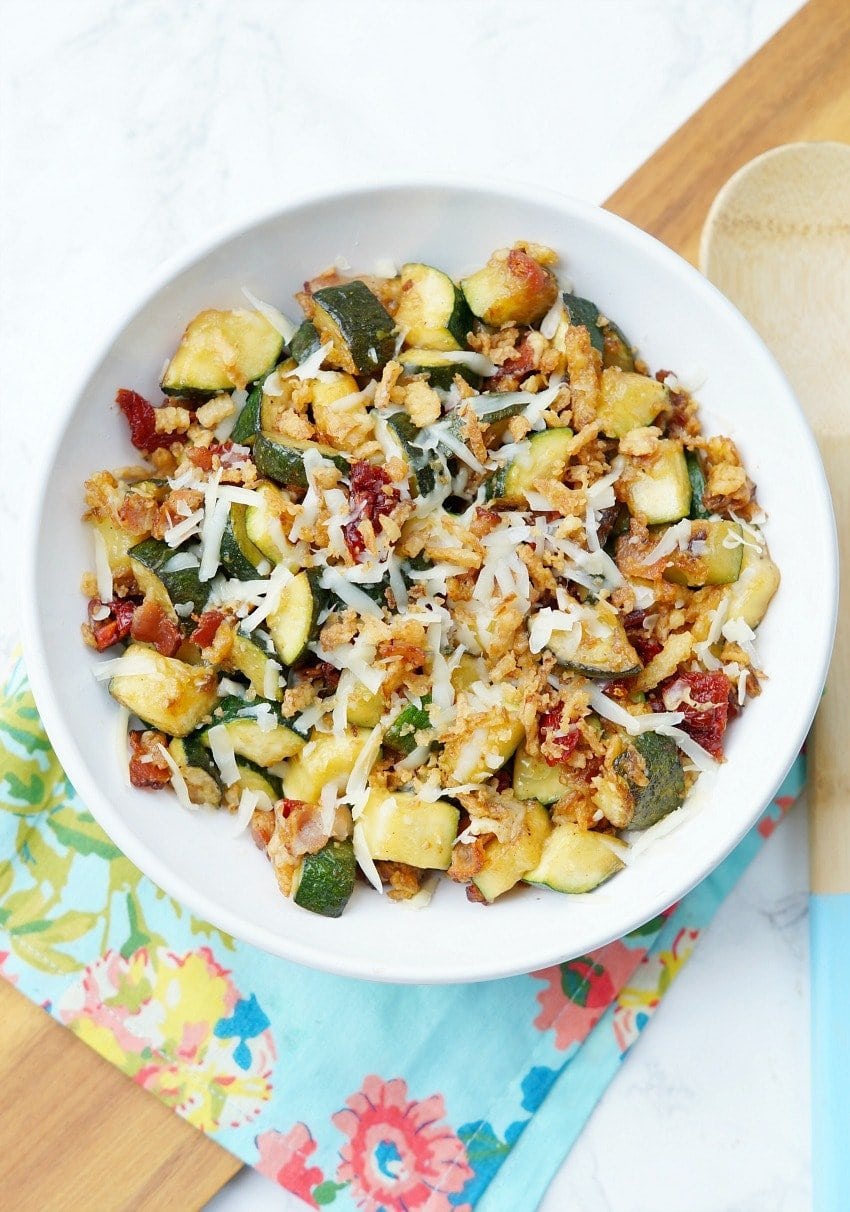 Zucchini with Sun Dried Tomatoes, Bacon, and Crispy Onions is a flavor packed side dish recipe that your family will ask for again and again this zucchini season!