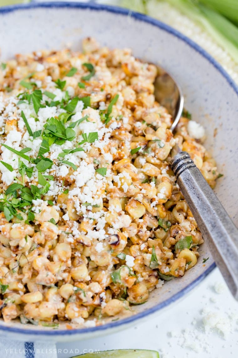 A close up of Mexican Street Corn Salad with a spoon in the bowl.