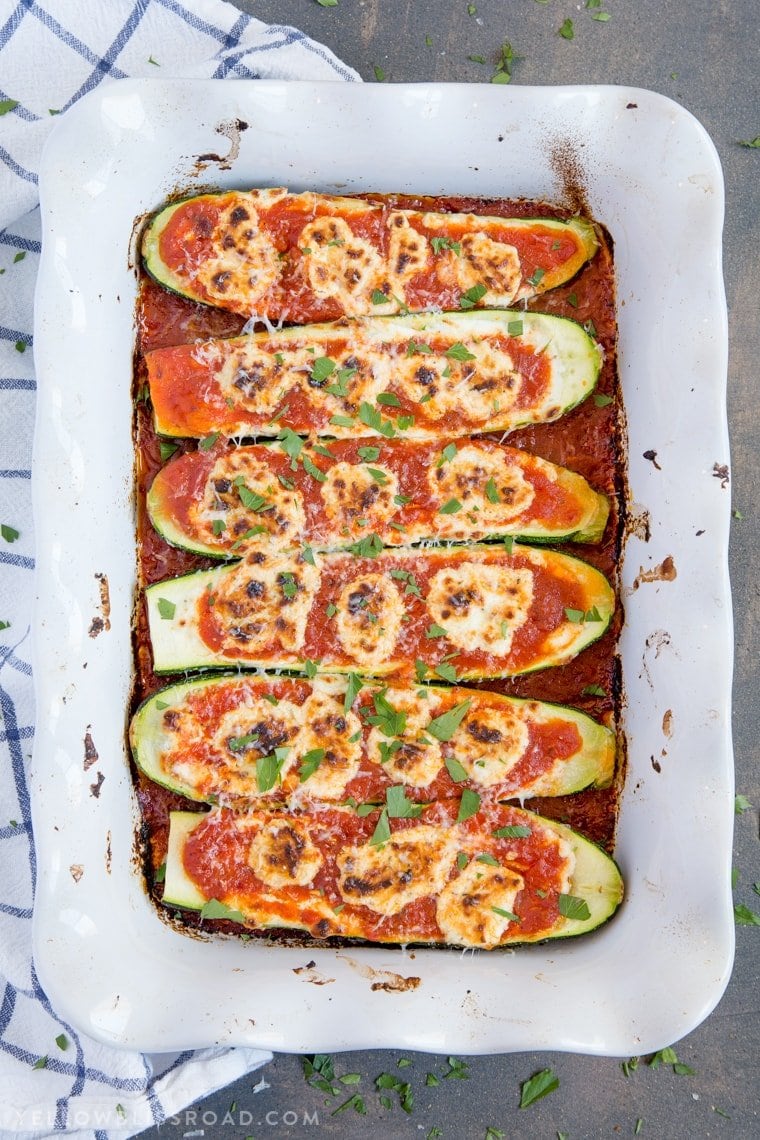 6 Goat Cheese & Marinara Stuffed Zucchini Boats in a white baking dish.