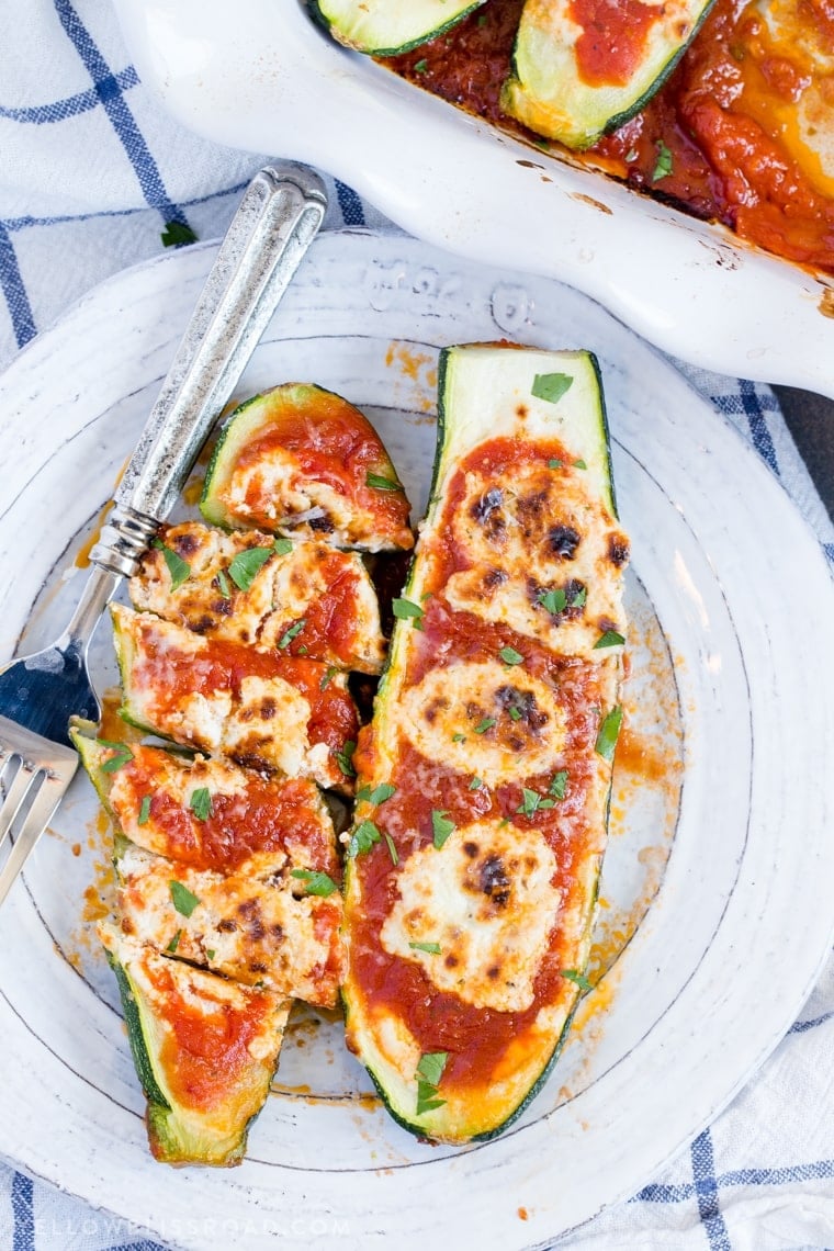 2 Goat Cheese & Marinara Stuffed Zucchini Boats on a plate, sliced.