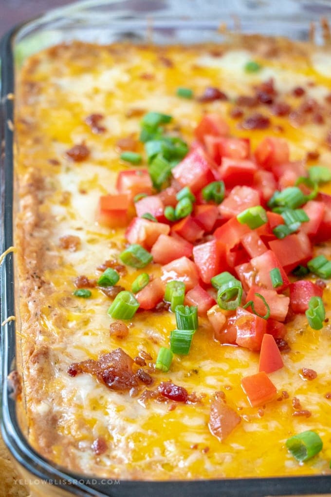 A pan of Refried Bean Dip with tomatoes and green onions.