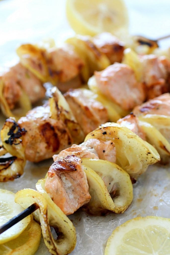 3 wooden skewers with salmon and sliced lemons