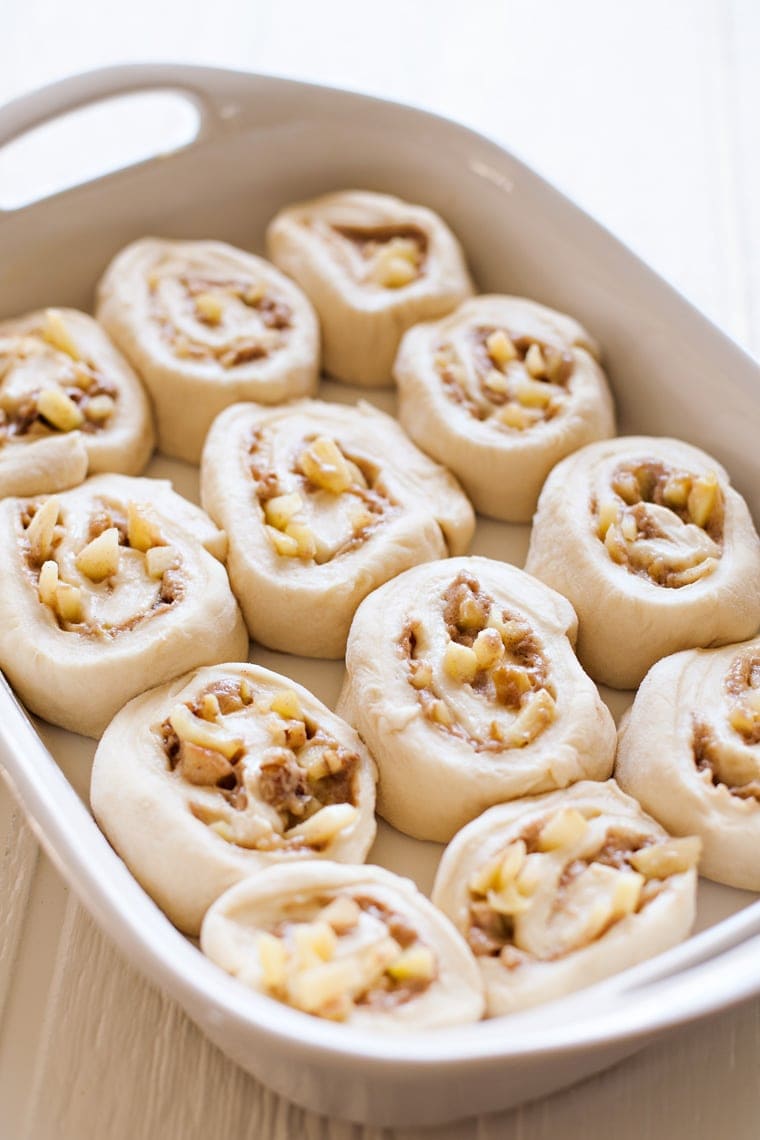 A white dish with unbaked cinnamon rolls