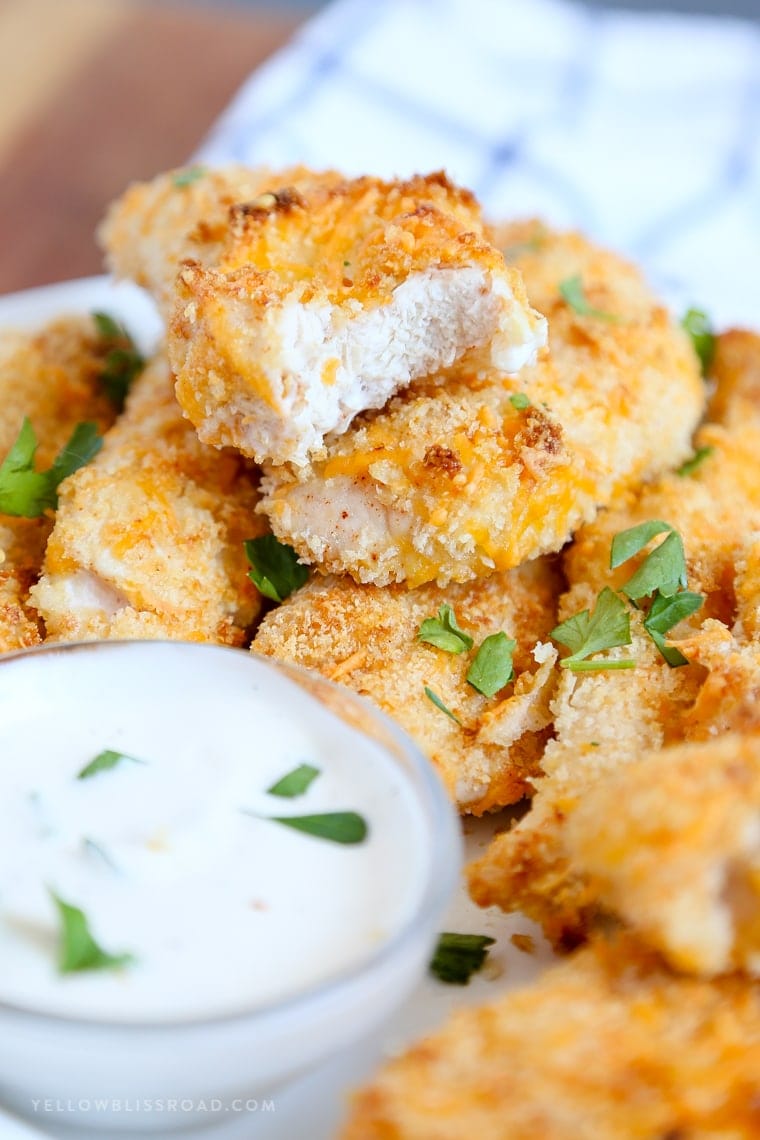 A stack of Baked chicken tenders with a bit taken out of one.