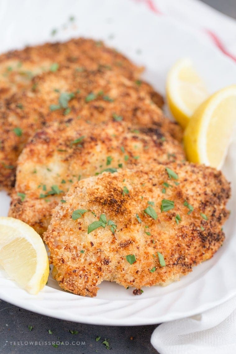 Crispy Garlic Parmesan Baked Chicken laying a a large platter with lemon slices