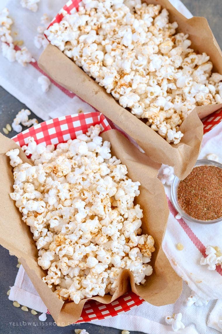 Hot Buttered Cajun Popcorn with homemade cajun seasoning in cute red and white containers.