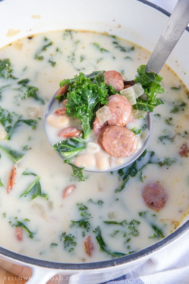 A pot of soup with sausage and kale