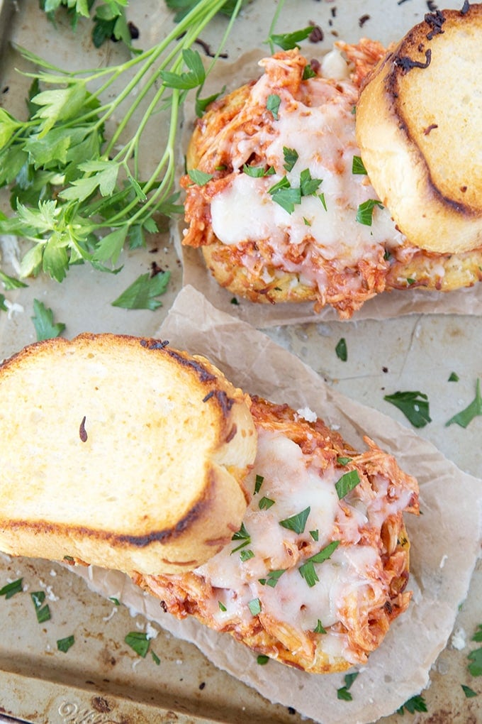 An overhead shot of two Shredded Chicken Parmesan Sandwiches on Texas Toast with the tops half off.