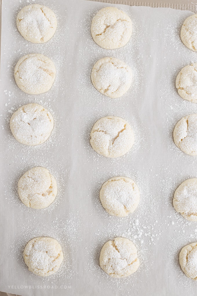 Nut free Snowball cookies dusted with powdered sugar on a baking sheet.