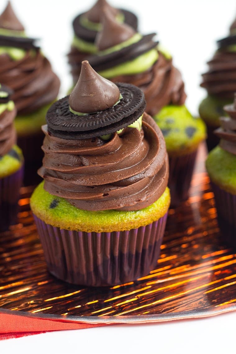 A green cupcake with chocolate frosting that looks like a witches hat