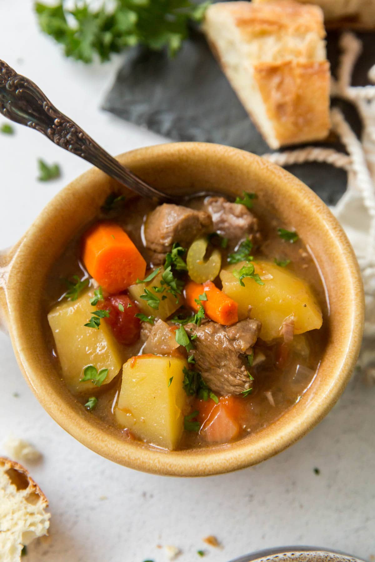 yellow bowl, spoon, parsley, bread, beef stew