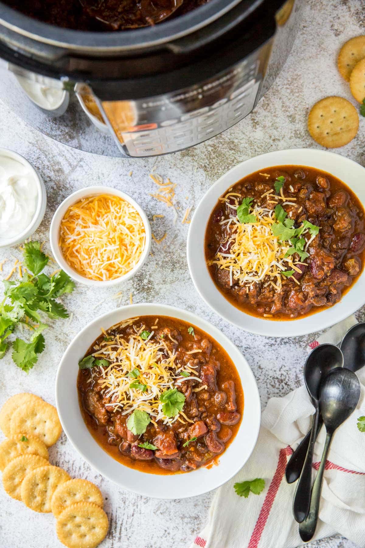 white bowls, chili, cheese, crackers, spoons, instant pot, cilantro