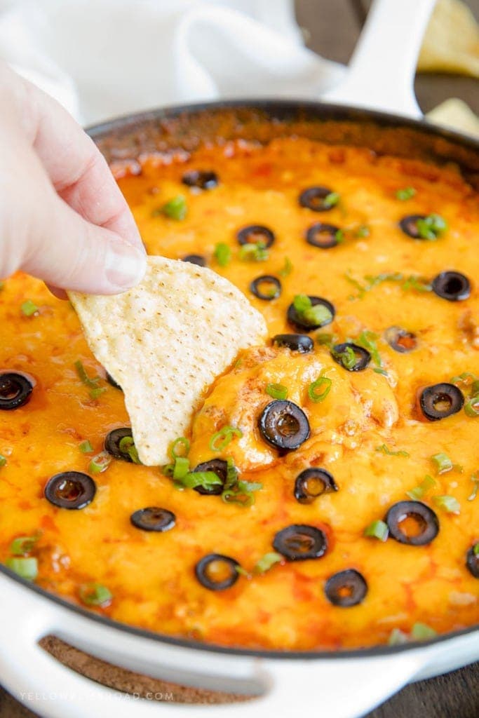 A chip dipping into beef enchilada dip