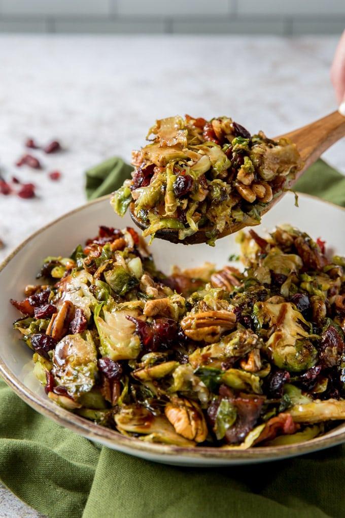 Brussels Sprouts salad on a wooden spoon held above a bowl