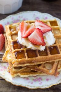 A stack of fluffy buttermilk waffles topped with whipped cream and drizzled in maple syrup is the perfect recipe for brunch. Learn all the tricks to fluffy waffles every time.