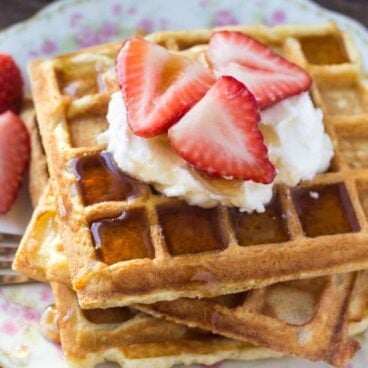 A stack of fluffy buttermilk waffles topped with whipped cream and drizzled in maple syrup is the perfect recipe for brunch. Learn all the tricks to fluffy waffles every time.