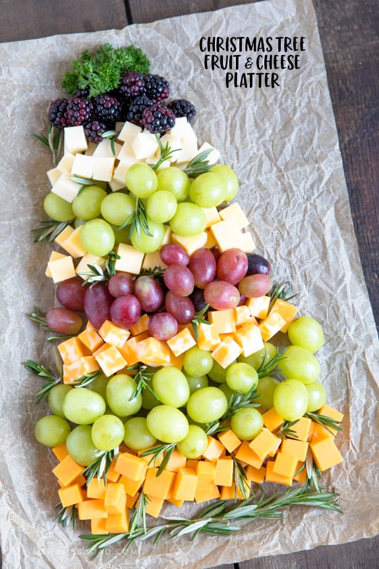 Fruit and cheese layered on a cutting board forming a christmas tree. 