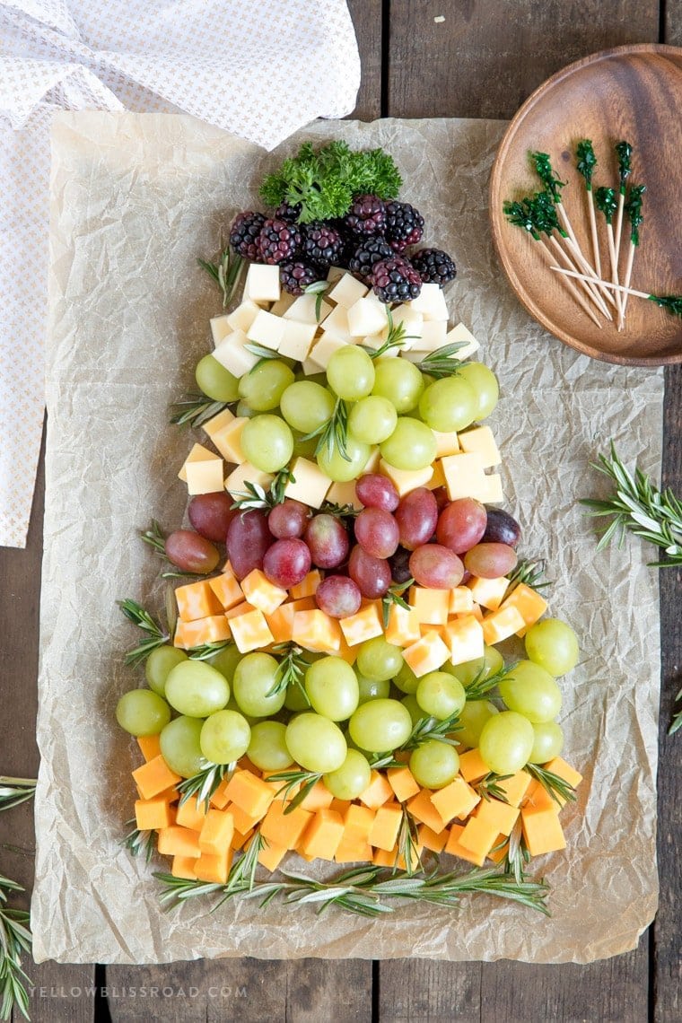 An overhead view of grapes, berries and cheese in the shape of a Christmas tree