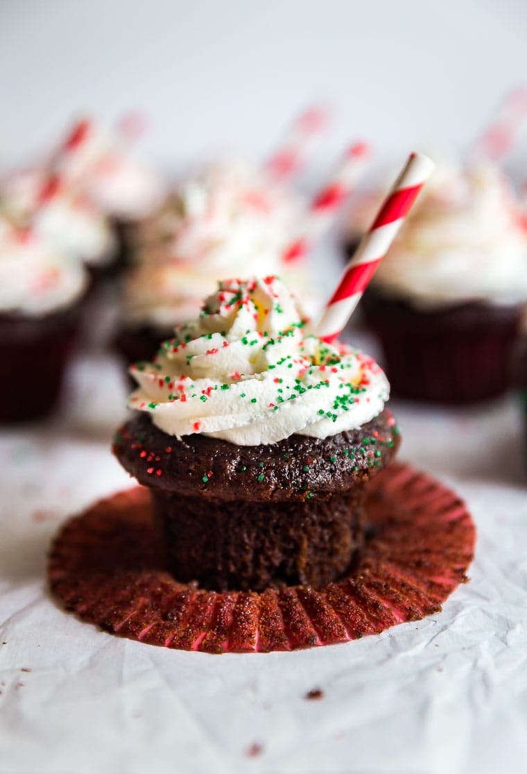 Peppermint Hot Chocolate Cupcakes in the background with a single one up front with the cupcake liner pulled down.
