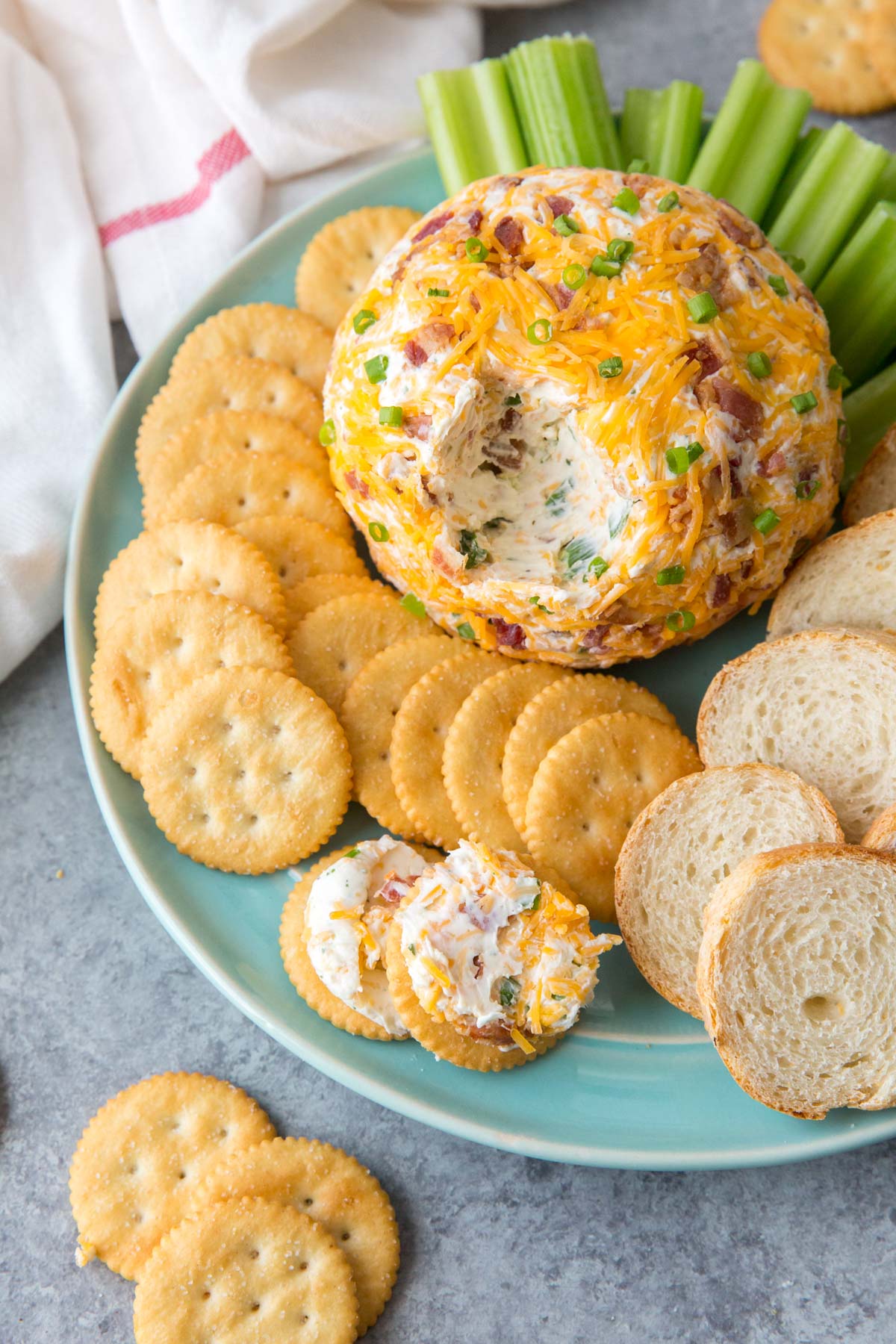 bacon cheddar cheeseball with crackers on a blue plate
