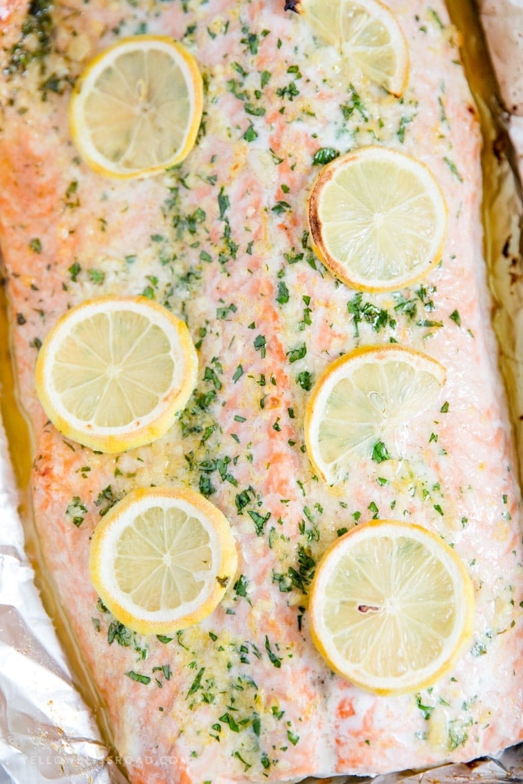 Piece of baked salmon covered with garlic butter and lemons